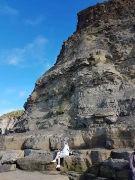 Fiona, painting, at the foot of cliffs in Staithes, North Yorkshire